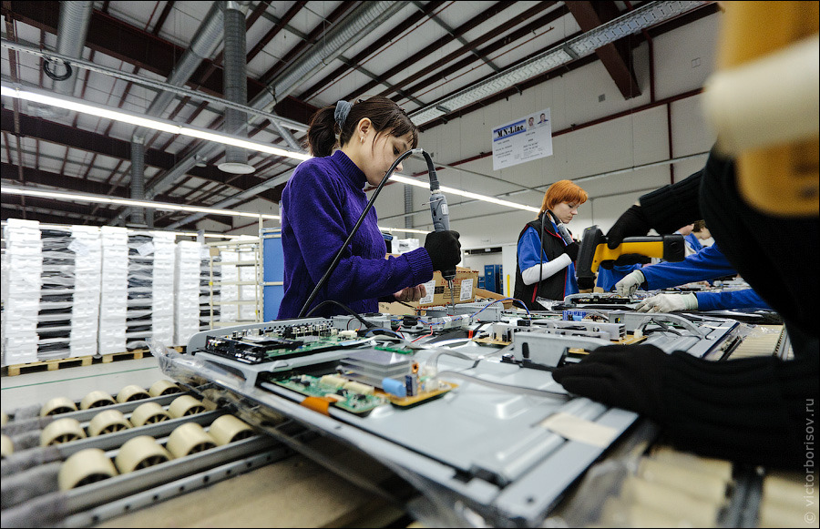 Производственный конвейер. Сборочная линия завода. Производство телевизоров. Сборщик на конвейере. Сбор телевизоров.