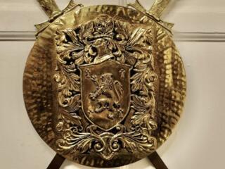 Старинный бронзовый геральдический щит с безудержным львом и мечами.